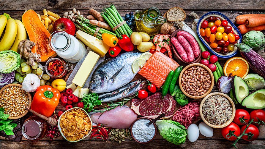gmos-nutrition-foods A wide spread of whole foods on a wooden table: fish, salmon, lean meats, beans, grains, cheese, fruit and vegetables